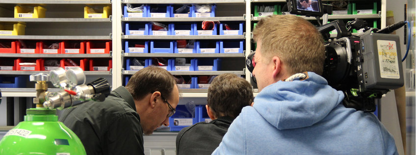 © S. Hejja/BGC Wissenschaftler vor einem Laborregal werden von einem Kameramann gefilmt.