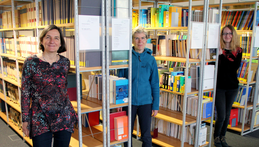Library team between the shelves of the library.