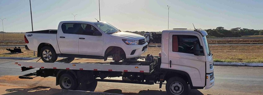 The broken car (a white pickup) on a white tower truck when it arrived at the car rental in Agua Boa. In the back you can see an evening atmosphere and in the front long shadows.