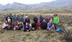Group of researchers gathered in front of a mountainous terrain with sparse vegetation.