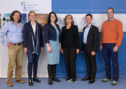 Gruppe von sechs Personen vor einem blauen und weißen Banner, das das Logo und den Namen des Deutschen Klima Konsortiums zeigt.